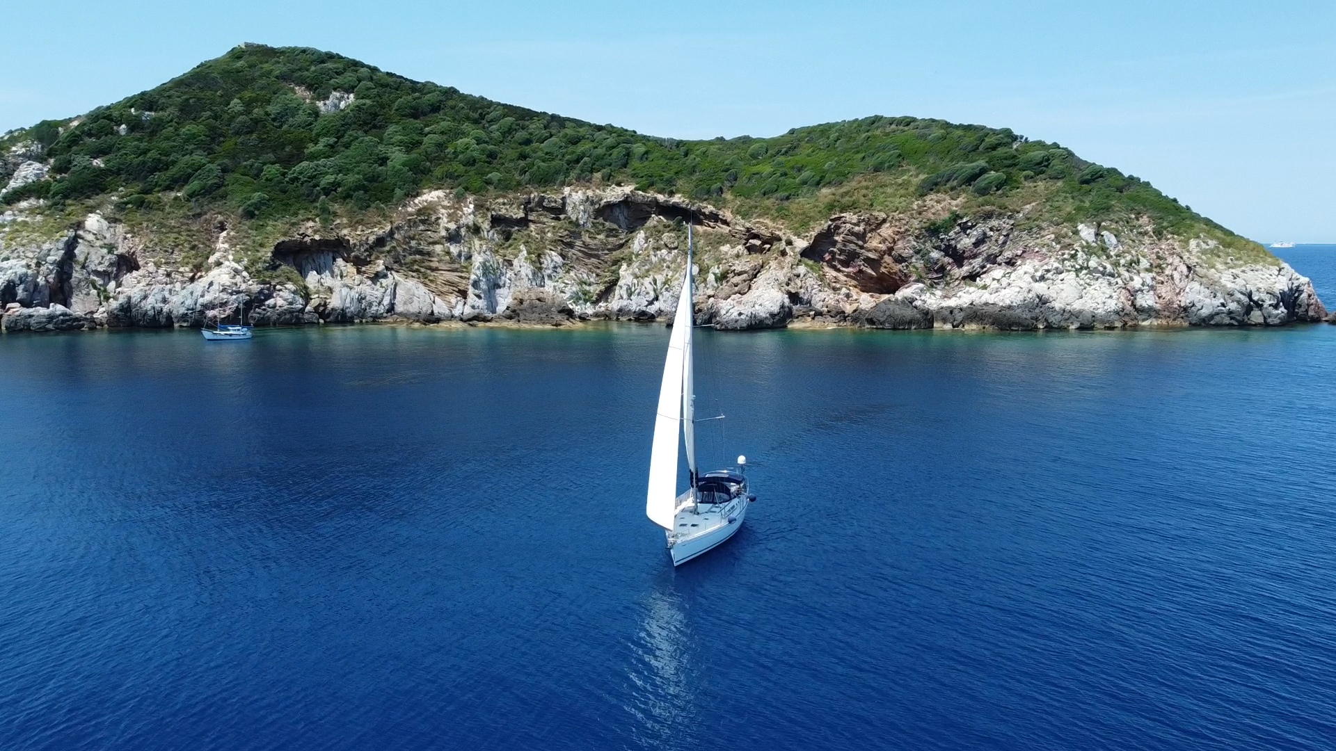 Aerial view of sailboat near island in crystal blue waters