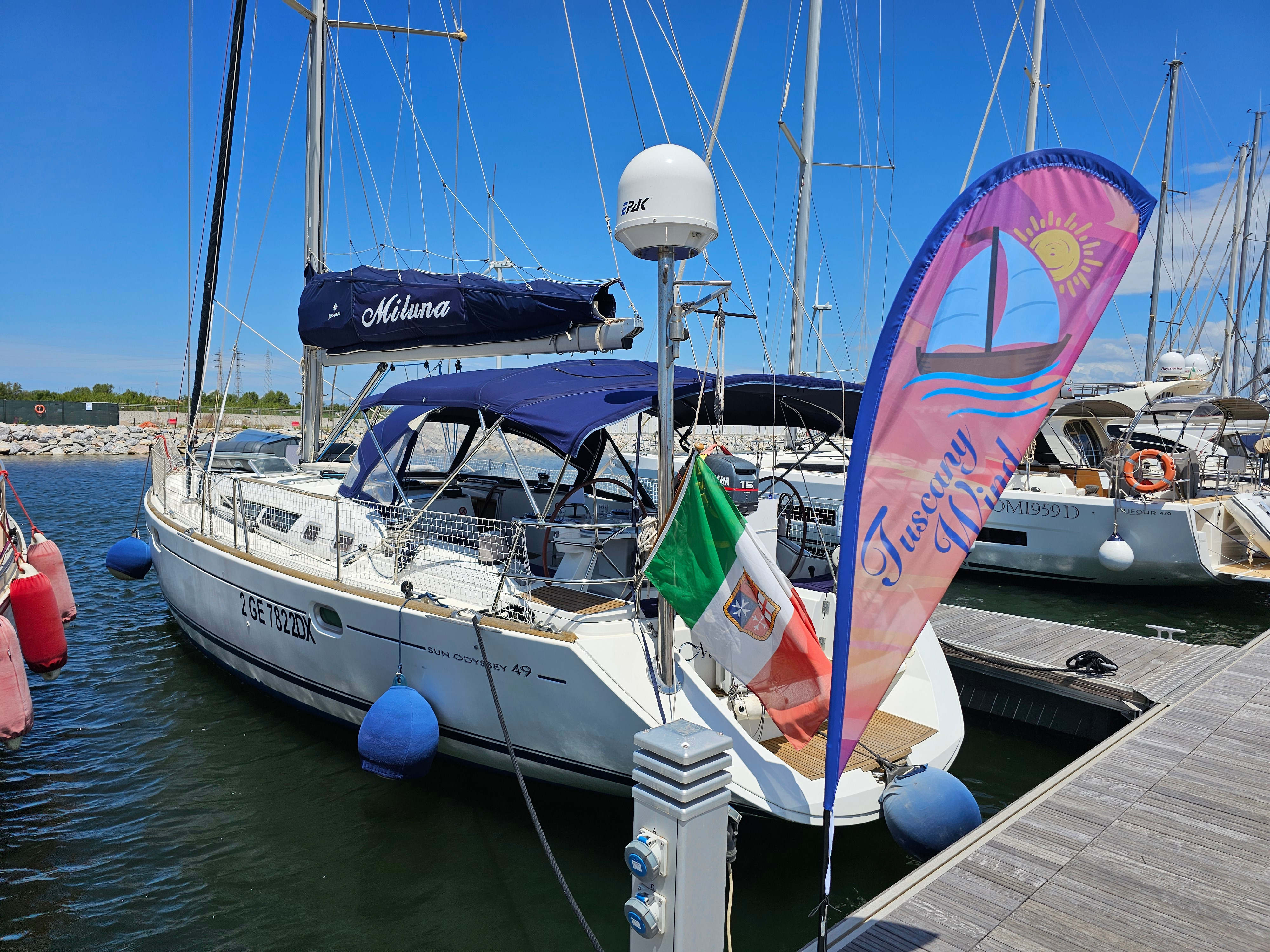 Tuscany Wind sailboat 'Miluna' docked at marina with flag