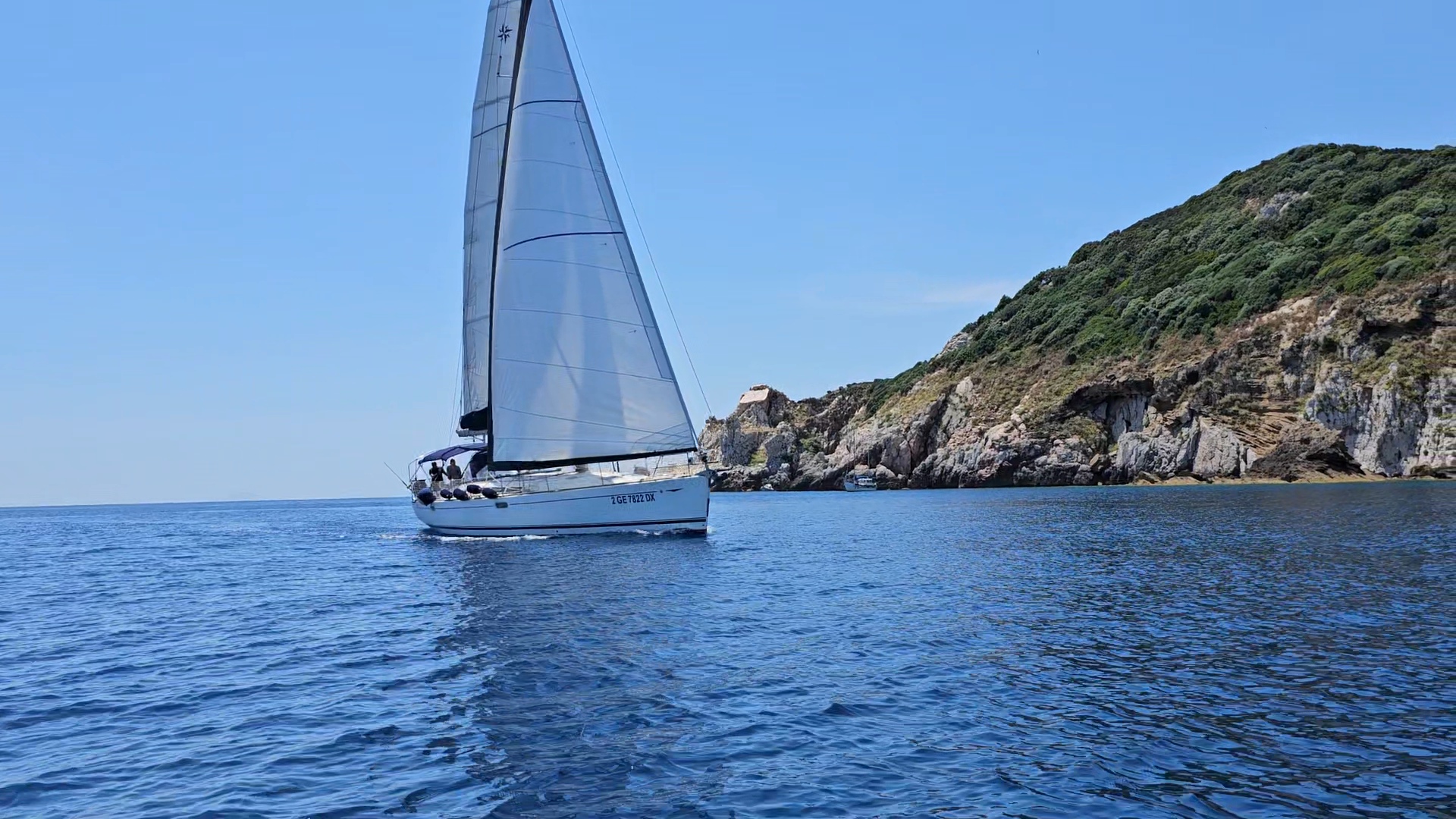 Sailing boat approaching green island coastline